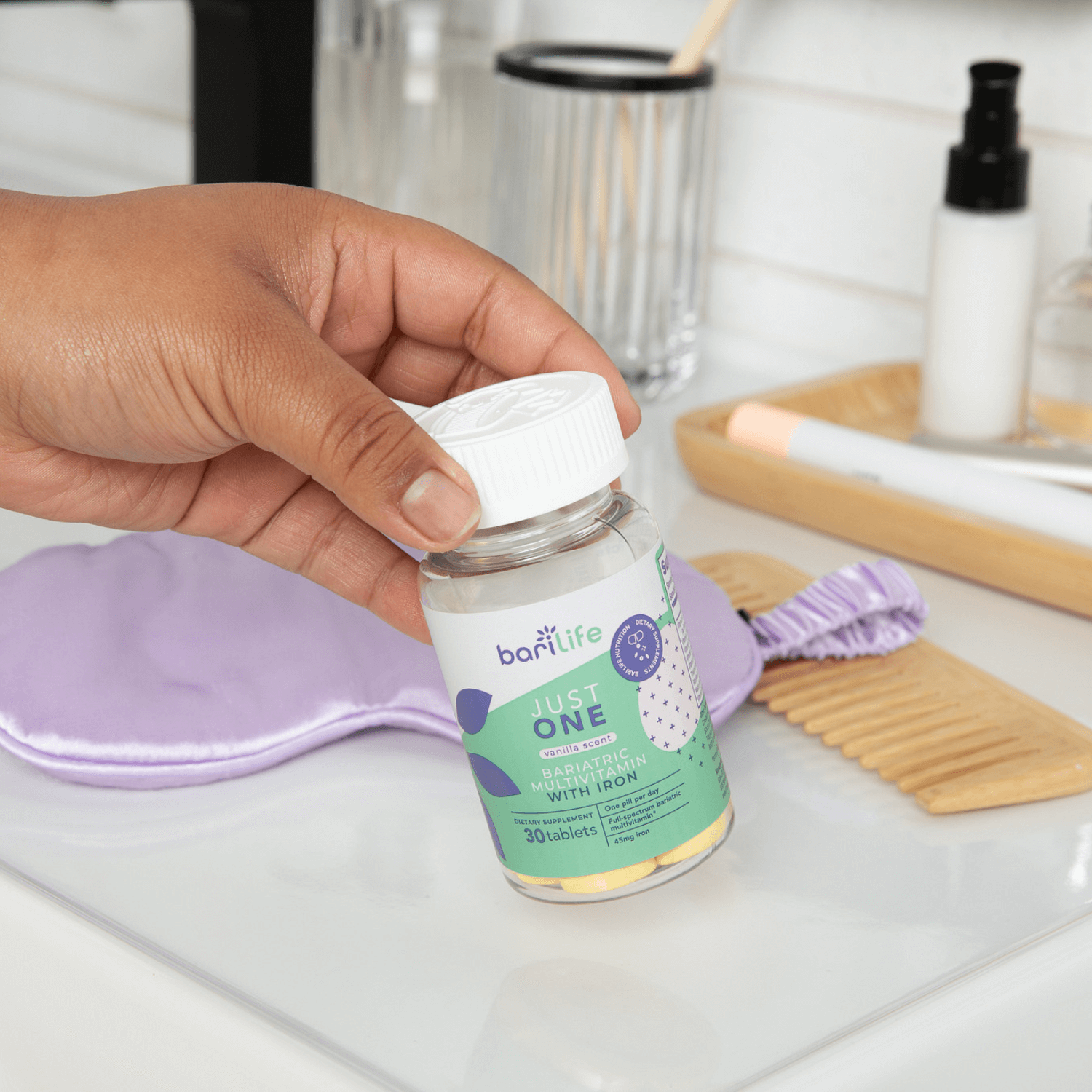 Hand holding Bariatric Multivitamin with Iron (45mg) bottle, featuring a clean vanity background.